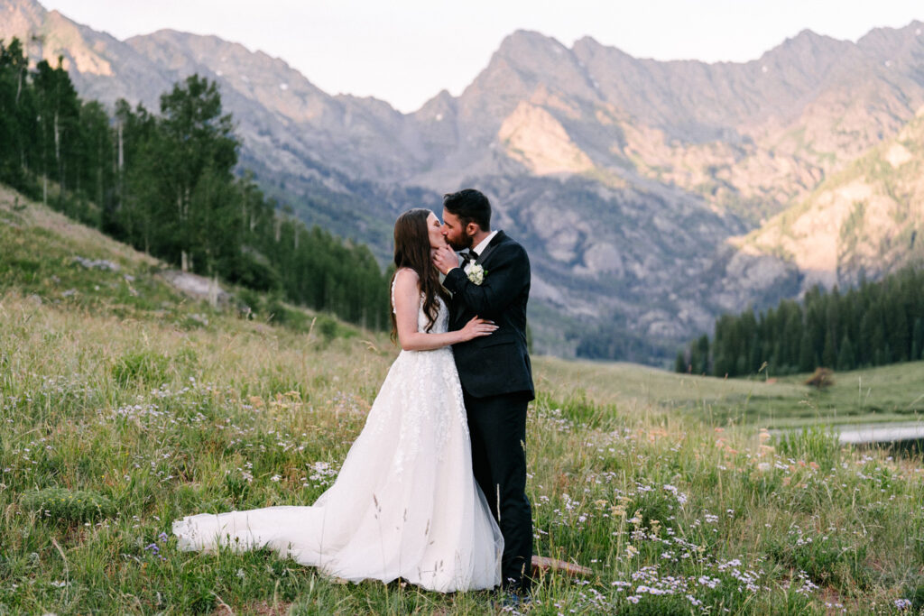 Newlyweds share a quiet moment overlooking a valley and pond at sunset