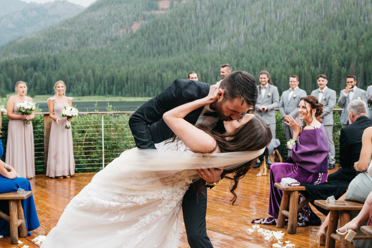 Newlyweds kiss under the ceremony arbor lakeside at their piney river ranch wedding