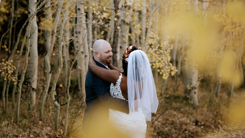 Newlyweds smile and embrace in a fall forest trail during their crested butte elopement