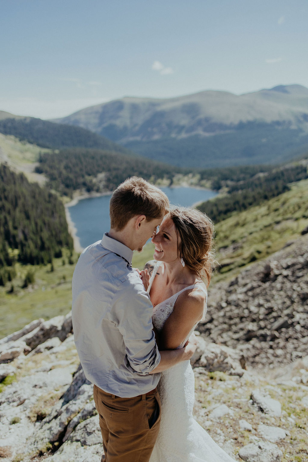 Newlyweds touch noses and smile big while standing a rocky hillside during their denver elopement