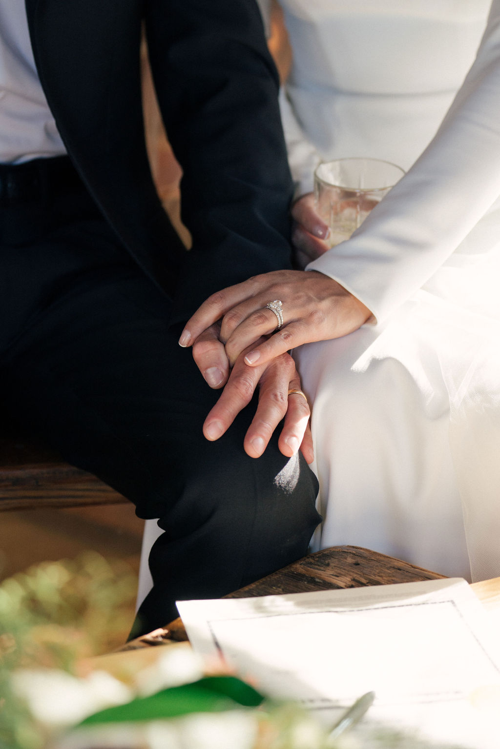 Details of newlyweds sitting and holding hands at their piney river ranch wedding