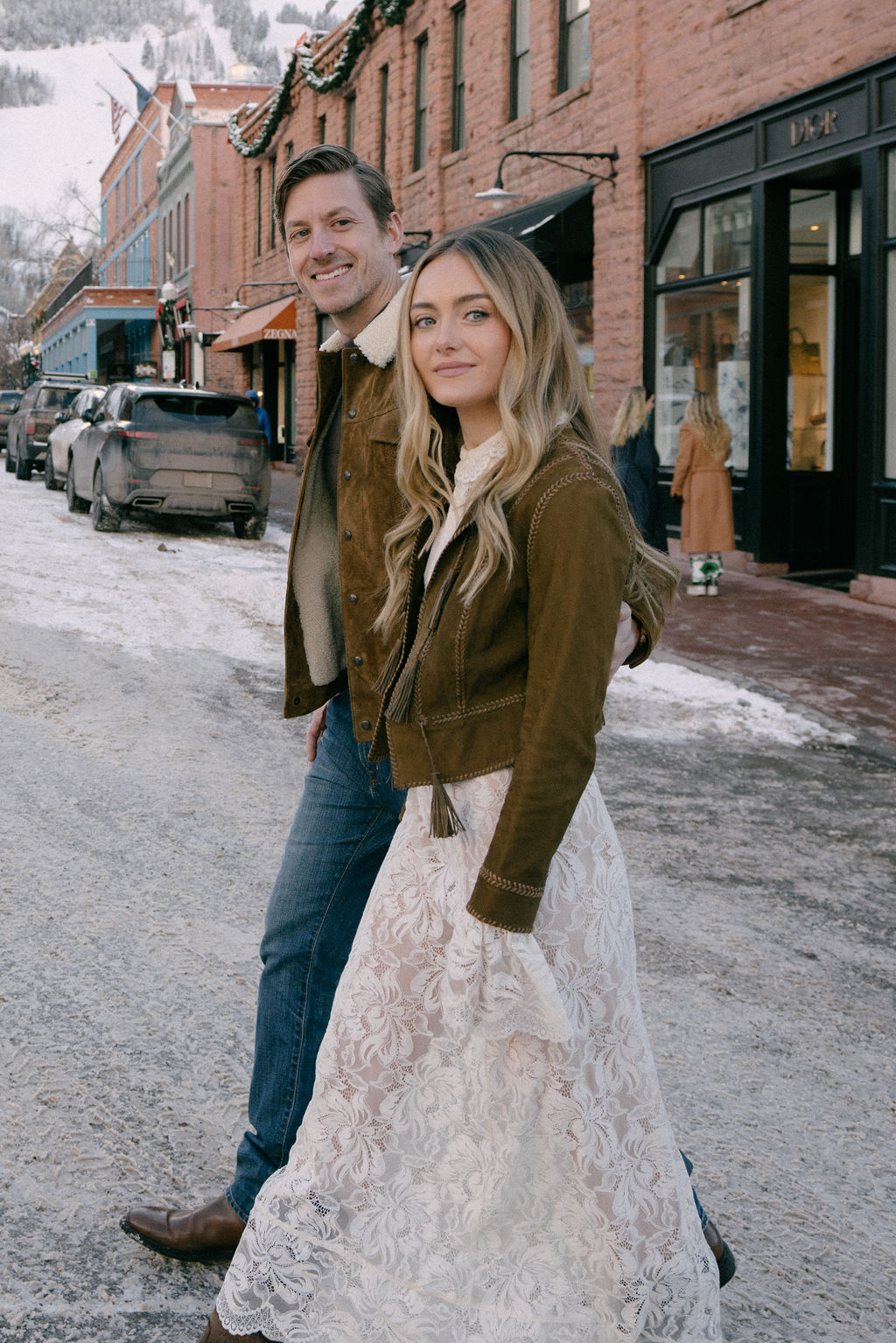 Newlyweds walk hand in hand across a downtown street