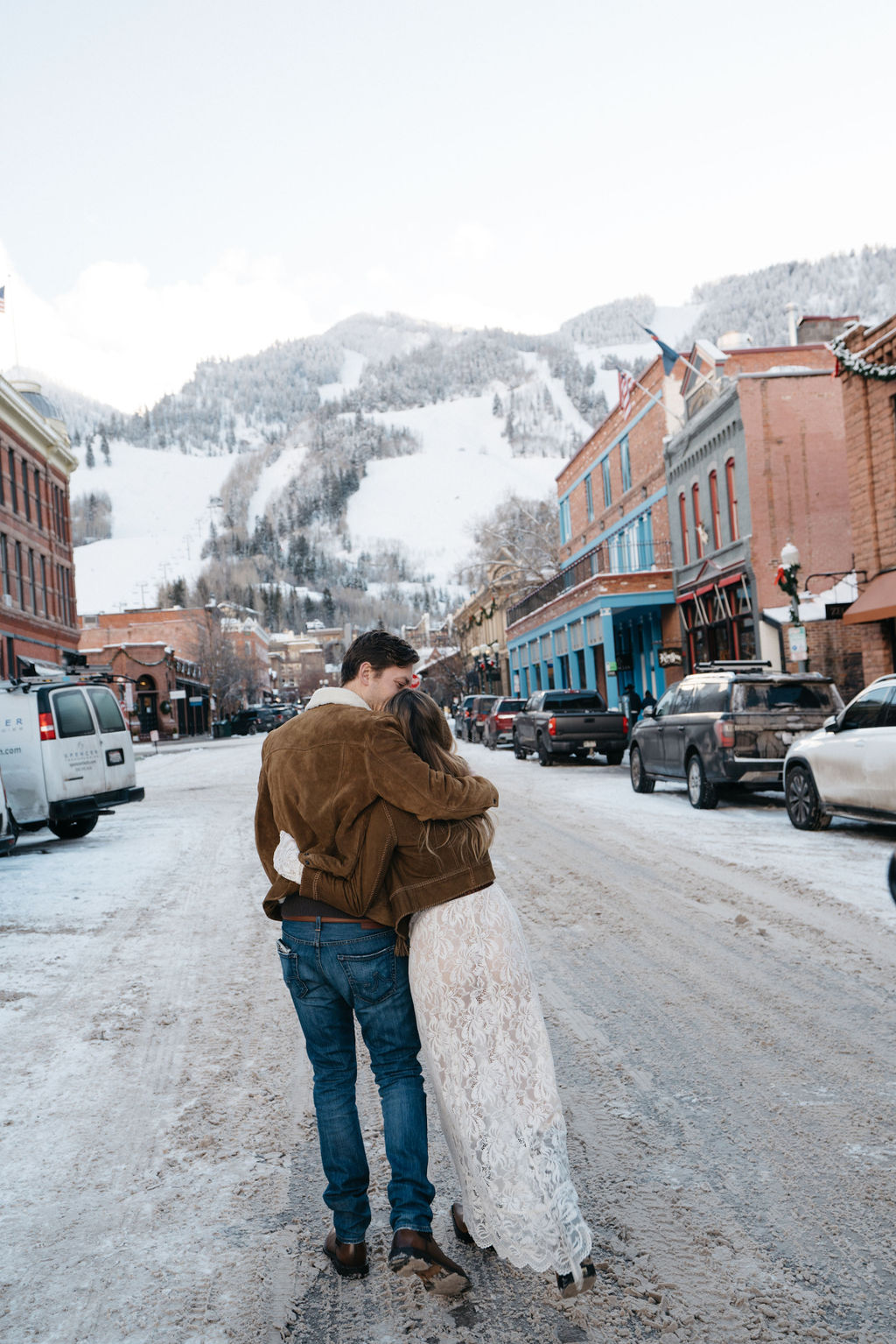 Newlyweds hug while walking through a downtown street in the snow