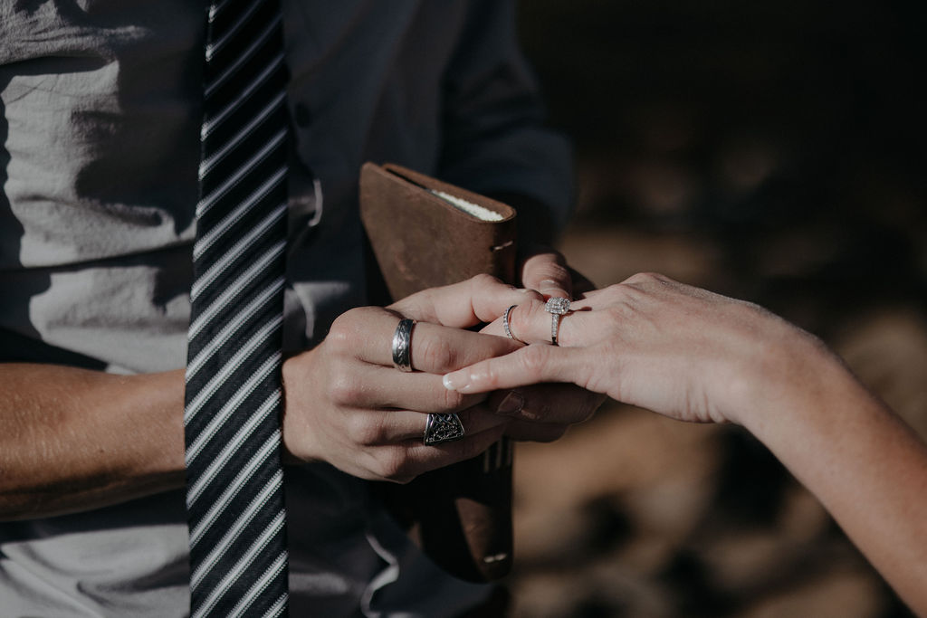 A groom puts hid bride's ring on her finger during their boulder elopement