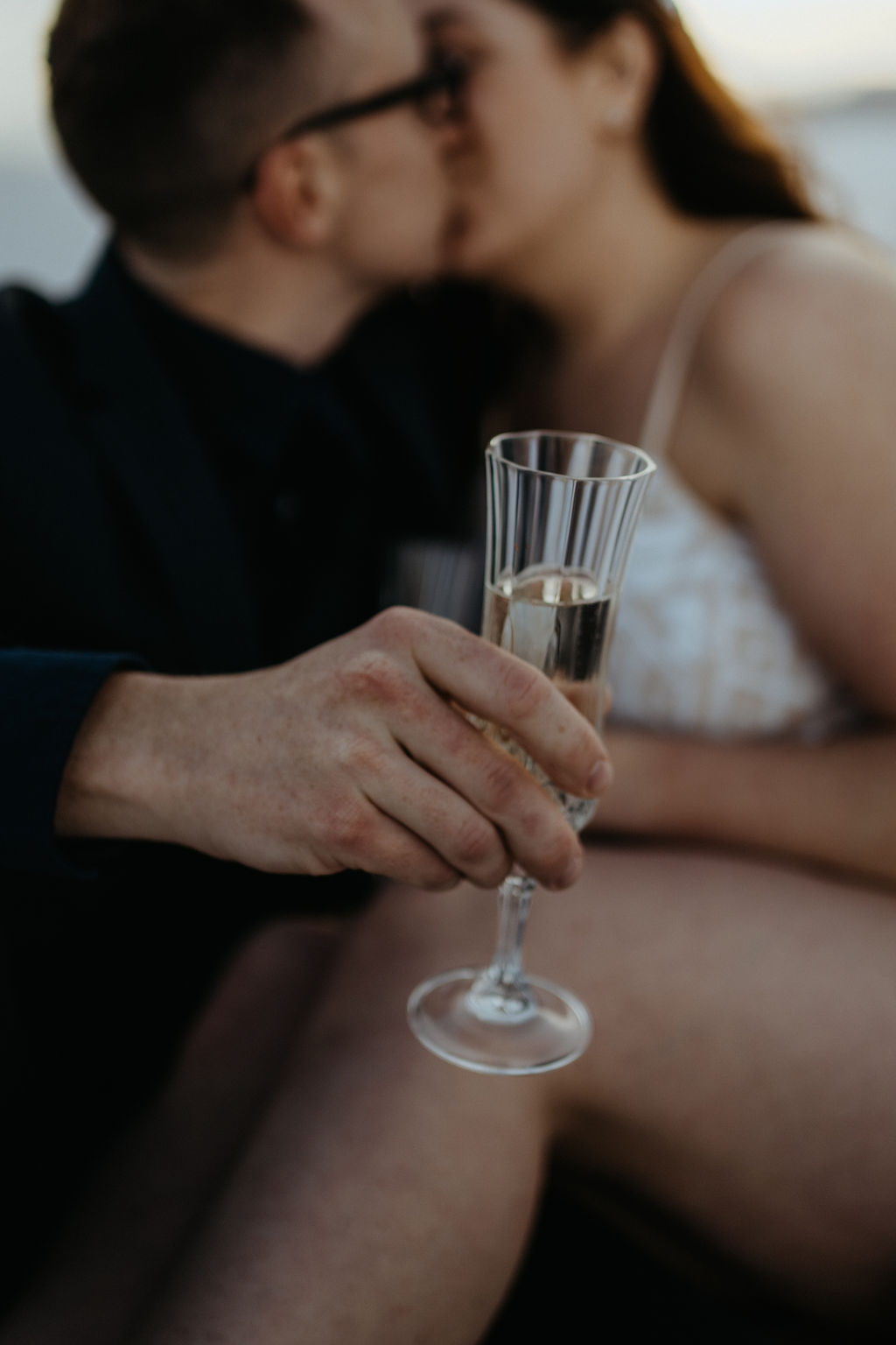 Newlyweds cuddle and kiss while sharing champagne