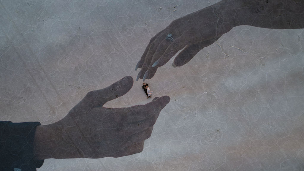 Newlyweds lay on the ground between two hands touching mural during their breckenridge elopement