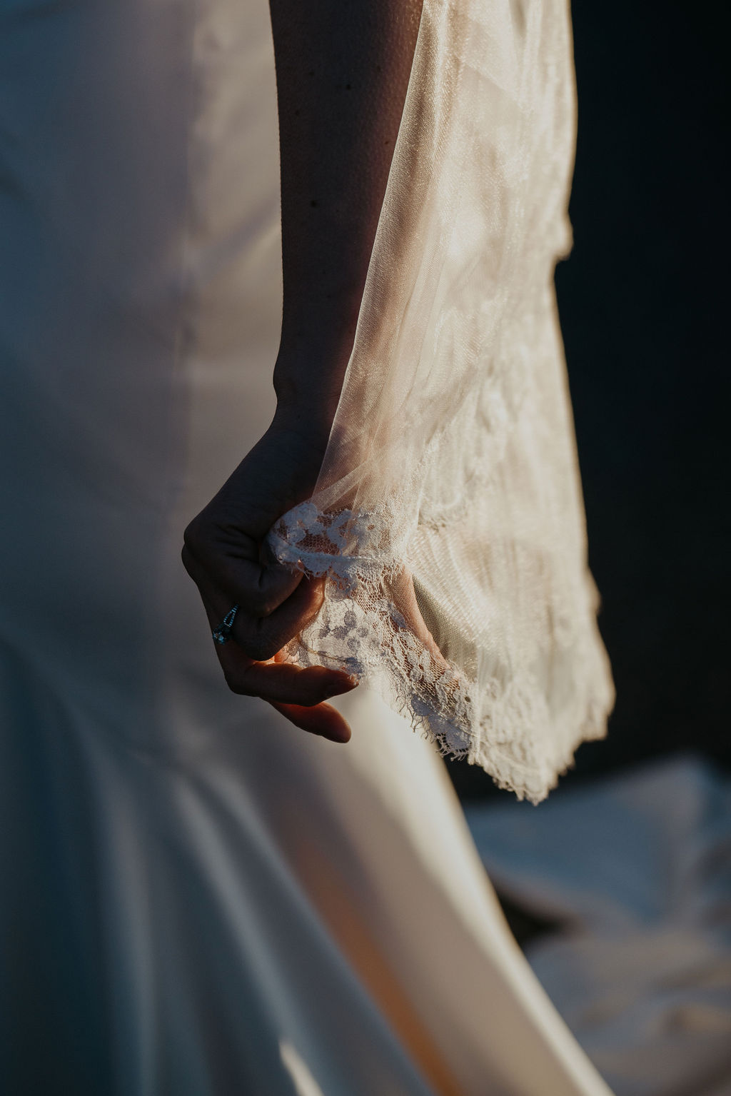 Details of a bride holding her lace embroidered veil at sunset during her breckenridge elopement