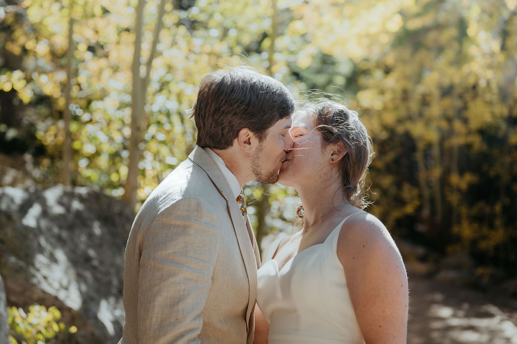 Newlyweds kiss in the fall aspen forest in a tan suit and silk dress at rocky mountain national park elopement