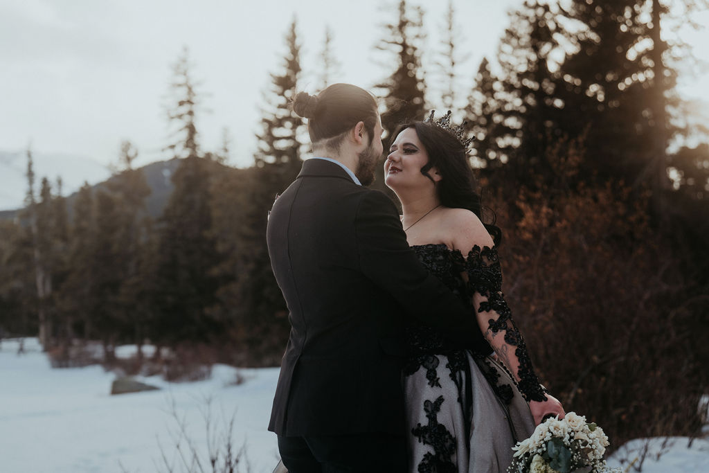 Newlyweds embrace for an intimate moment in a black dress and suit in a snowy telluride elopement