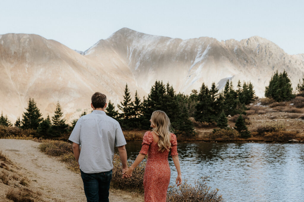 free wedding venues colorado loveland pass, couple wanlks hand in hand with mountains in the background