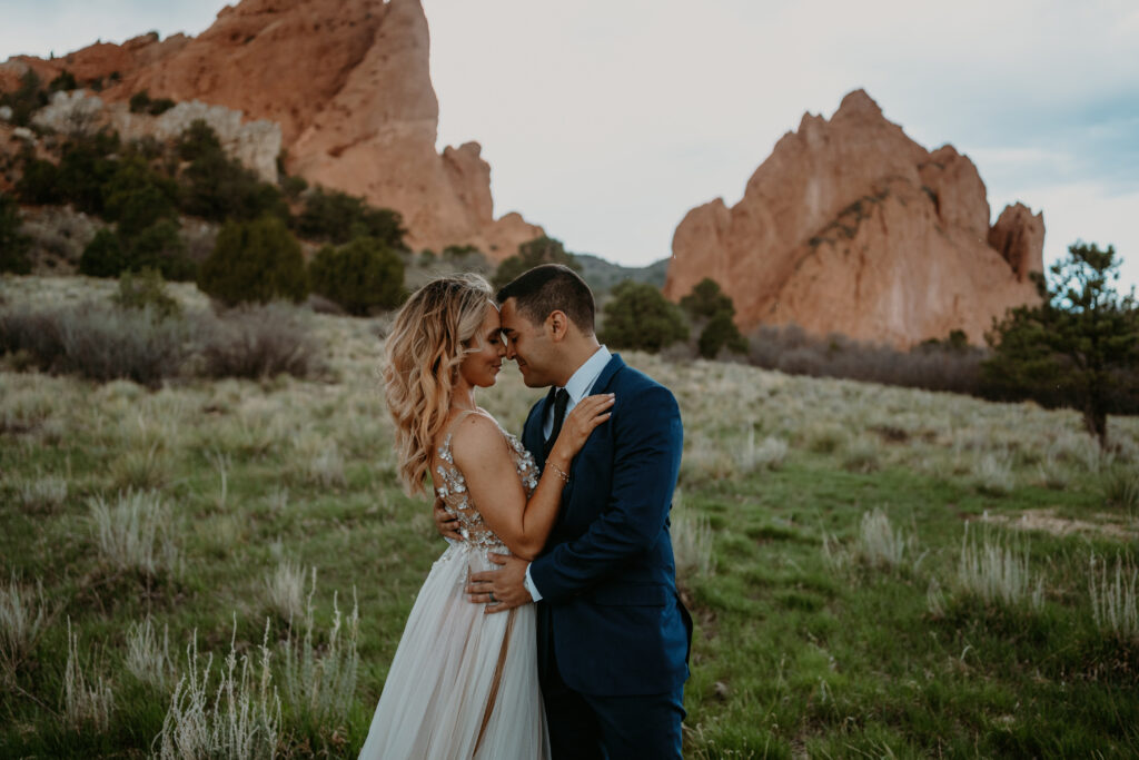 garden of the gods elopement - couple snuggles in together in front of towering rock formations at garden of the gods on their elopement day