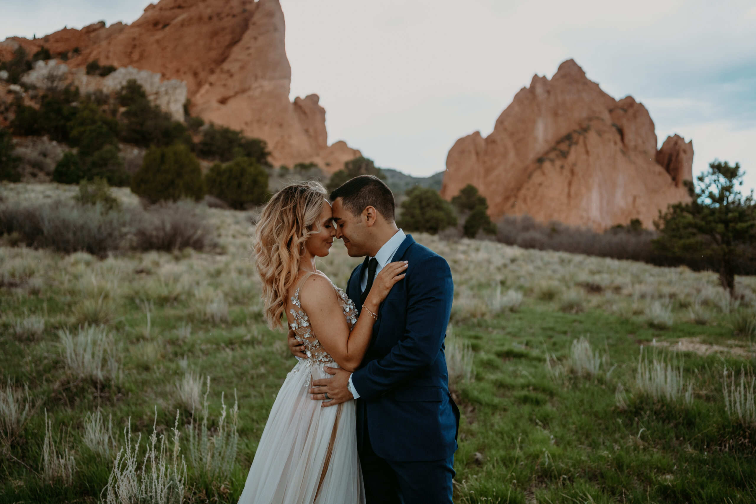 garden of the gods elopement - couple snuggles in together in front of towering rock formations at garden of the gods on their elopement day