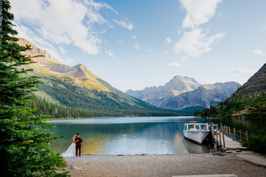 couple stands on the shore line of their glacier national park elopement